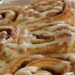 cinammon rolls in a baking dish with icing on them