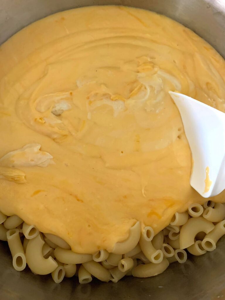 adding cheese sauce to homemade macaroni and cheese