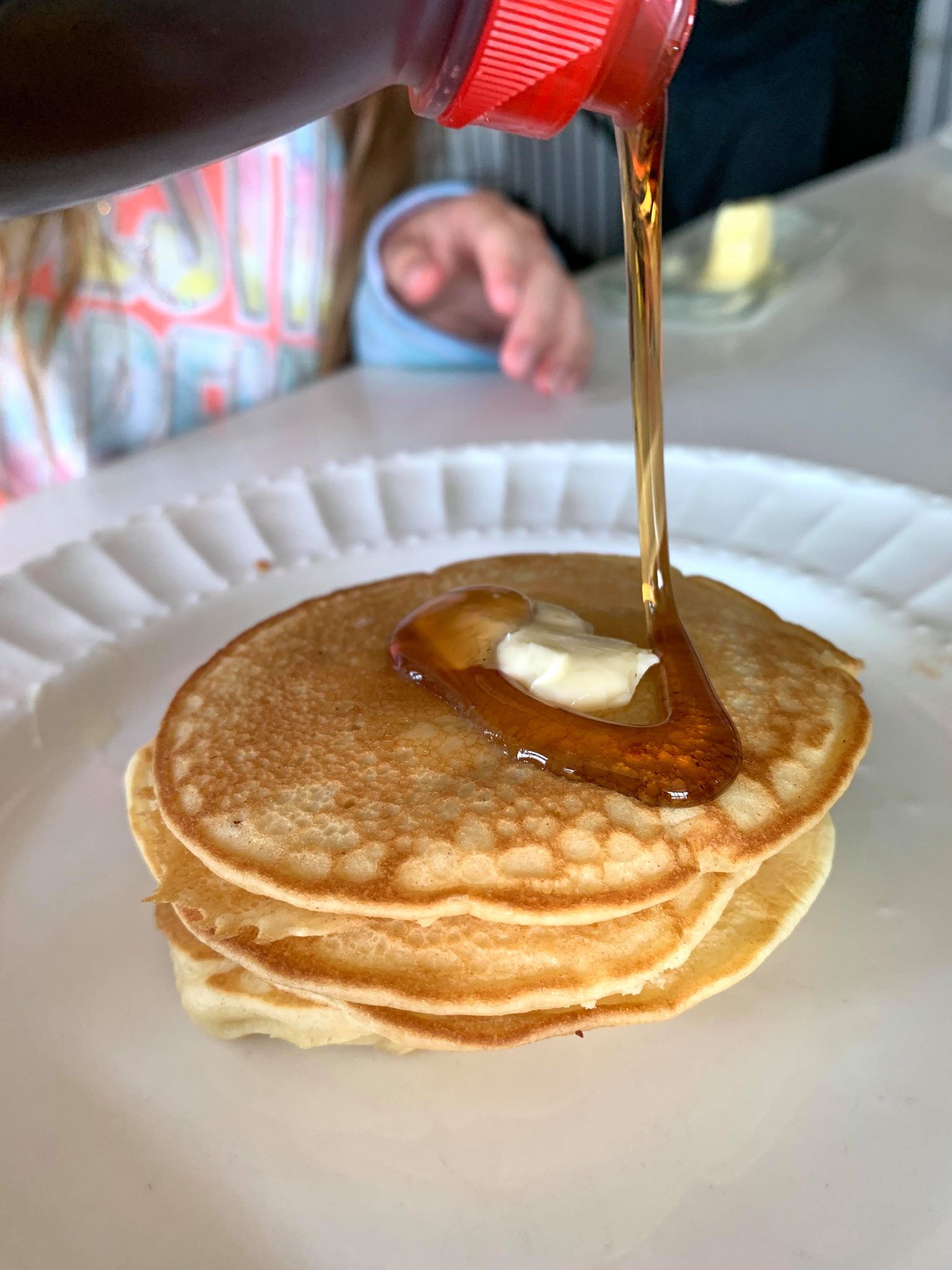 putting syrup on homemade pancakes